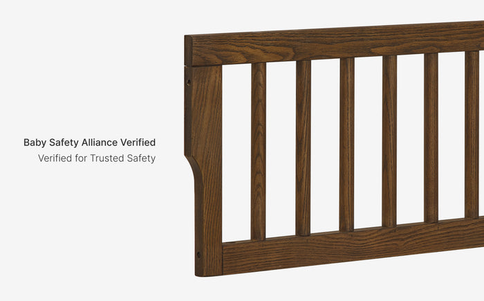 Wooden baby crib rail with 'Baby Safety Alliance Verified' text on a white background