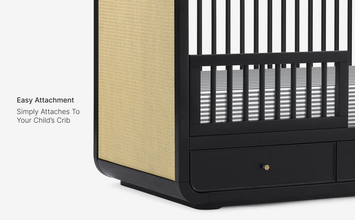 Black crib with beige side panel and text 'Easy Attachment Simply Attaches To Your Child's Crib'.