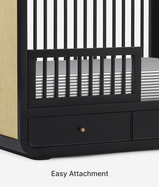 Black crib with beige side panel and striped mattress, featuring 'Easy Attachment' text.