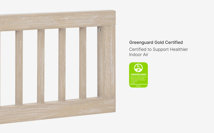 Wooden crib with Greenguard Gold certification label on a white background