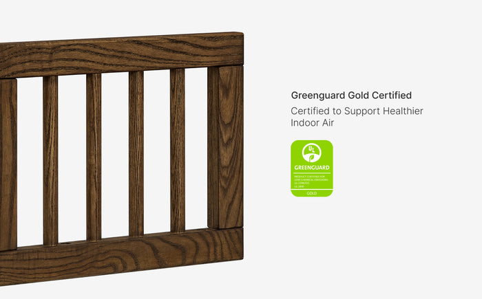 Wooden crib with Greenguard Gold certification label on a white background