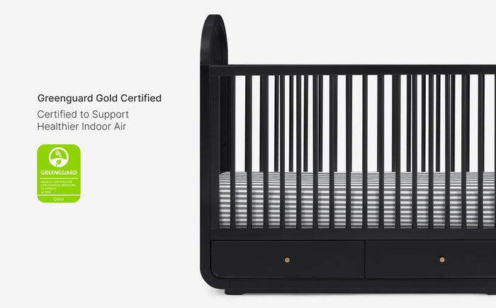 Black crib with Greenguard Gold certification label on a white background