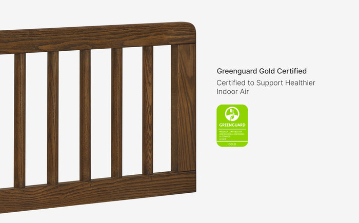 Wooden crib with Greenguard Gold certification label on a white background
