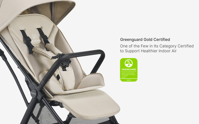 Beige stroller seat with black straps on a white background, featuring Greenguard Gold certification badge.