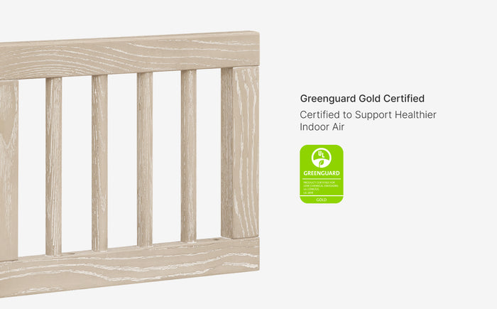 Wooden crib with Greenguard Gold certification label on a white background