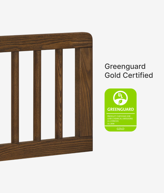 Wooden crib with Greenguard Gold Certified label on a white background