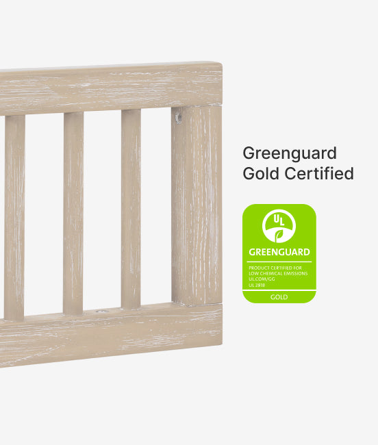 Wooden crib with Greenguard Gold Certified label on a white background