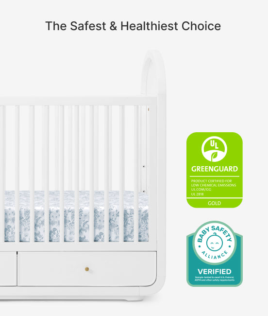 White crib with Greenguard Gold and Baby Safety Alliance verified badges on a white background