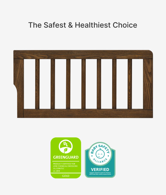 Wooden baby crib with GreenGuard Gold and Baby Safety Alliance verified badges on a white background.
