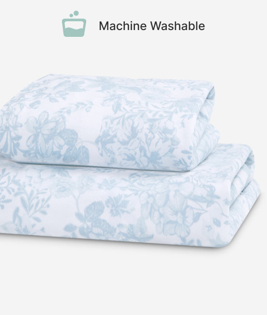 Folded blue and white floral patterned fabric with 'Machine Washable' text and icon on a light gray background