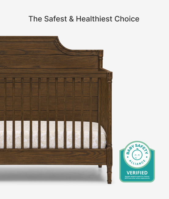 Wooden crib with white mattress and Baby Safety Alliance verified badge on a white background