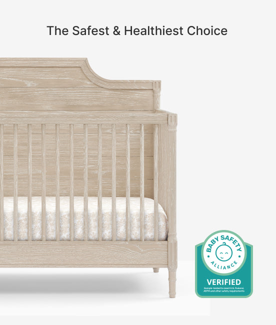 Beige crib with a white mattress and Baby Safety Alliance verified badge on a white background