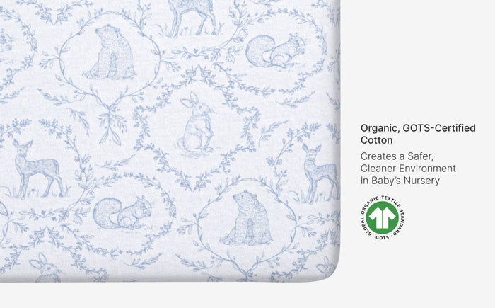Patterned organic cotton sheet with animal designs and GOTS certification label on a white background