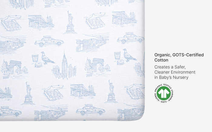 Baby crib sheet with blueprints pattern and GOTS certification label on a white background