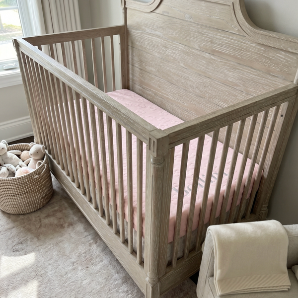 Wooden crib with pink mattress in a nursery setting