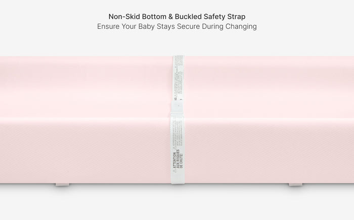 Pink changing pad with a safety strap on a white background