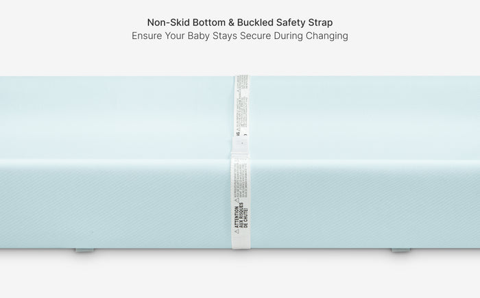 Light blue changing pad with a white safety strap on a white background
