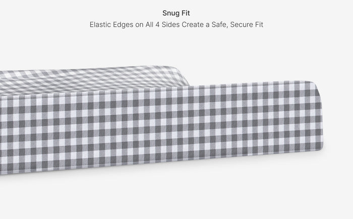 Gray and white checkered fitted sheet on a mattress with text about snug fit and elastic edges.