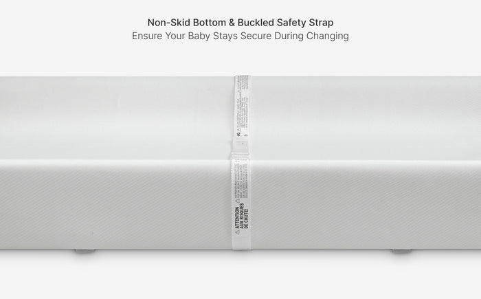 White changing table with non-skid bottom and buckled safety strap on a white background