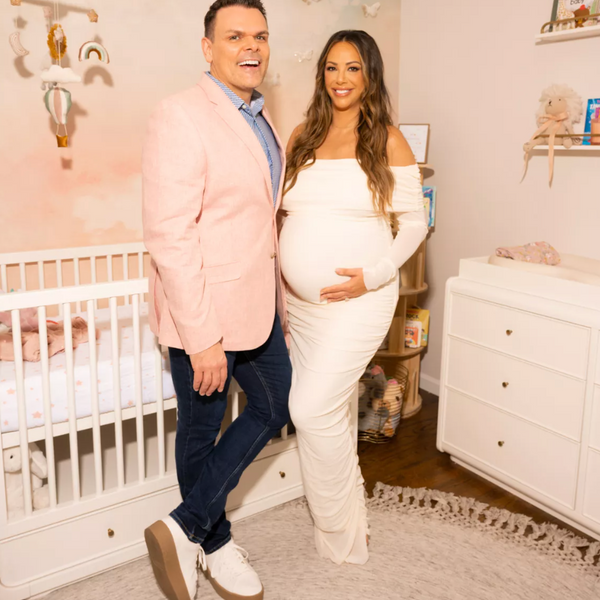 Man and pregnant woman standing in a nursery room.